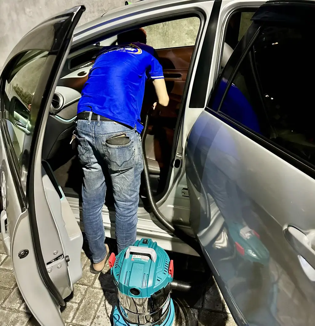 Porish Car technician vacuuming car interior at customer's garage